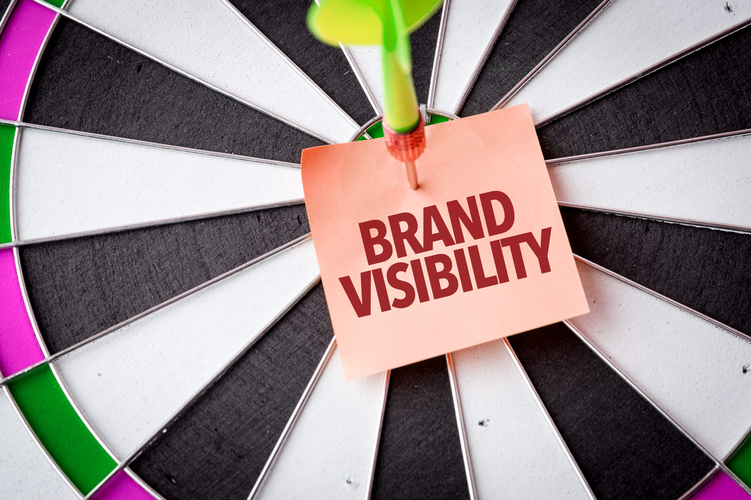 A sticky note with the words brand visibility pinned on a dart board.
