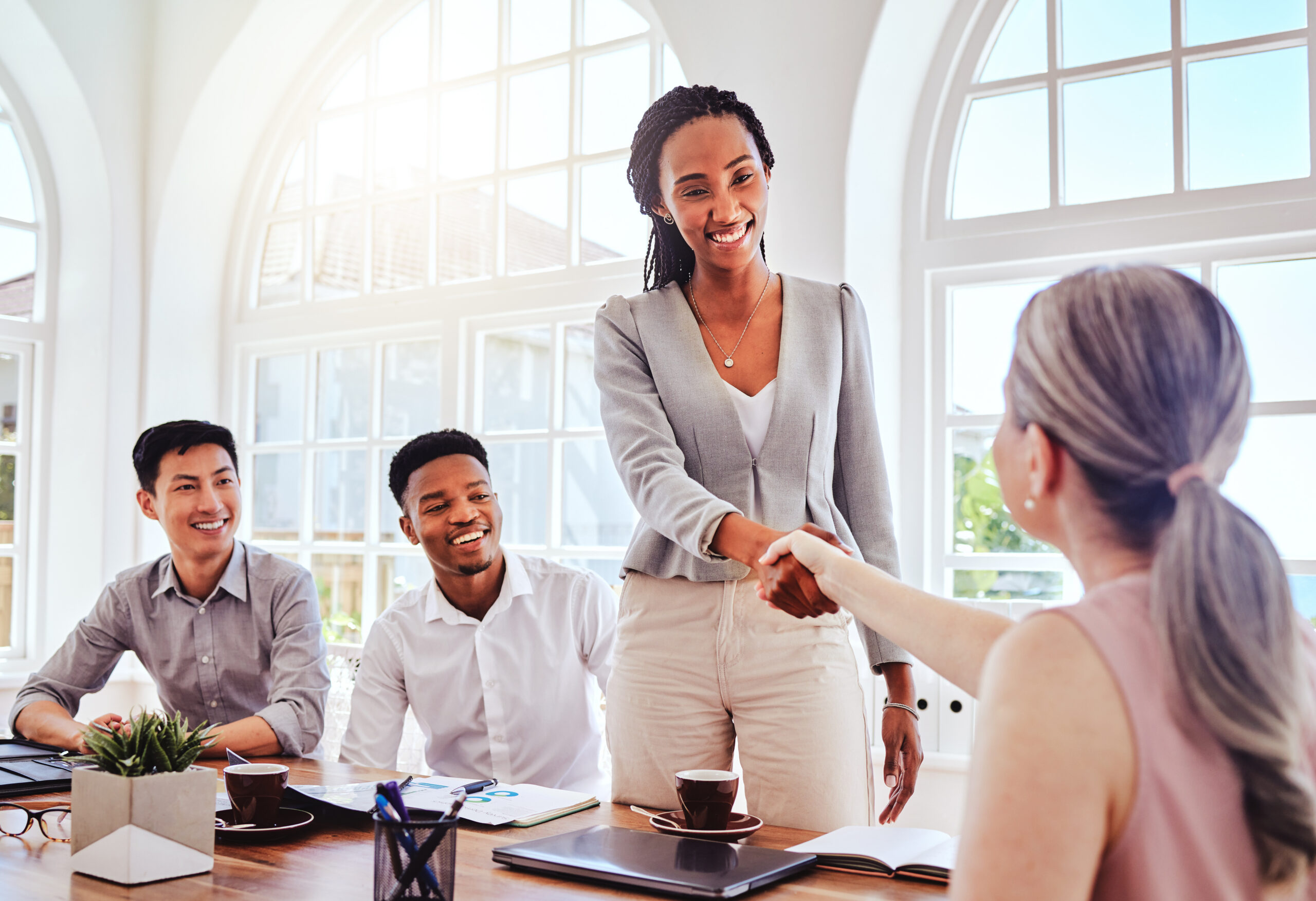 Team members welcoming a confident new hire during a professional office meeting.